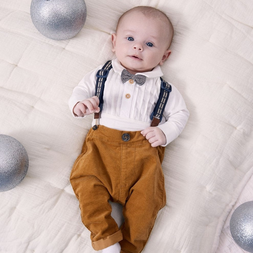 baby boy wearing cord trousers with braces and a bow tie bodysuit