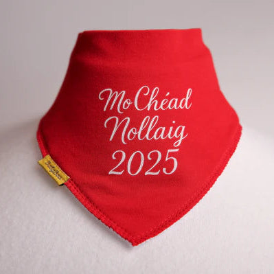 Red bib with 'Mo Chéad Nollaig 2025' text on a light  background