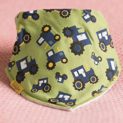 green baby bib with tractor pattern on a pink background