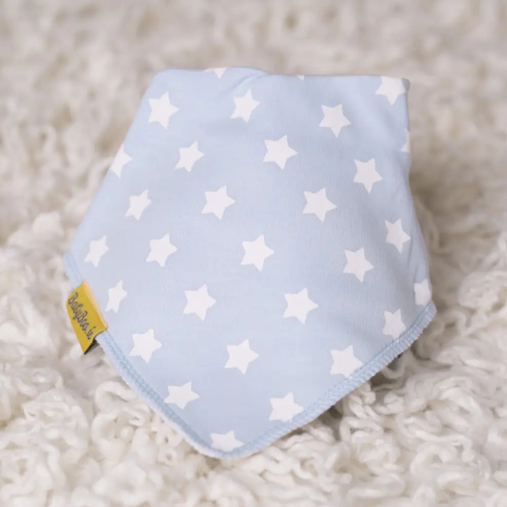 Blue baby bib with white star pattern on a fluffy white surface