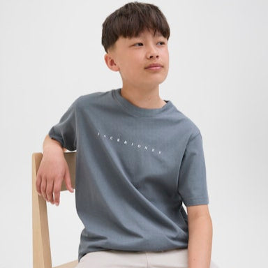 boy wearing a blue t-shirt with text, sitting on a chair against a white background