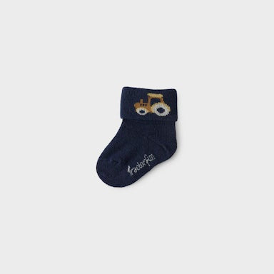 Navy blue baby sock with a tractor design on a light grey background