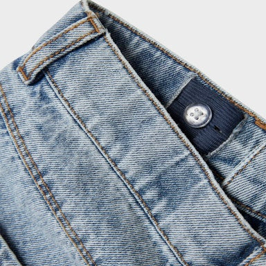 Close-up of a blue denim jacket with a button on a light grey background