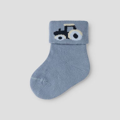 Blue baby sock with a tractor design on a light grey background