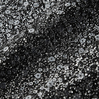 Close-up of black sequin fabric with a pattern of small silver sequins.