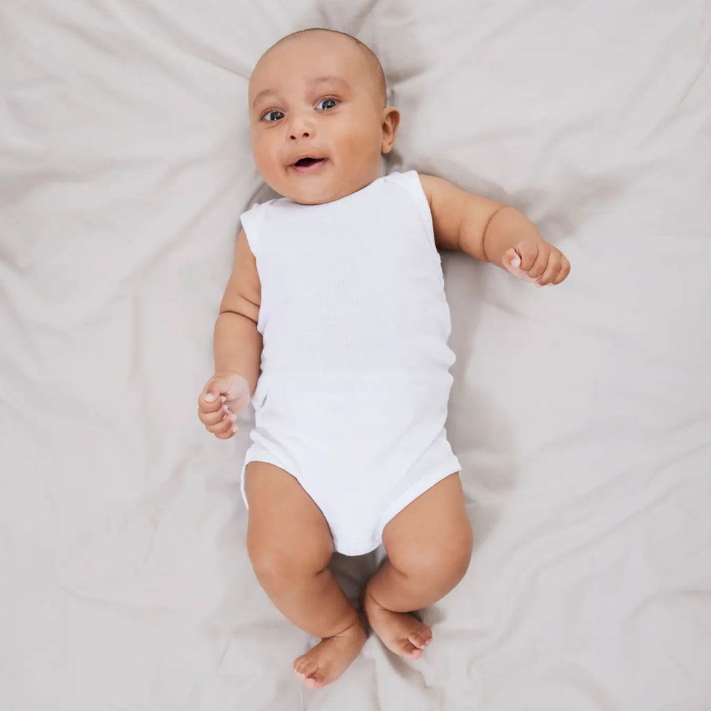 Baby in a white onesie lying on a light  blanket