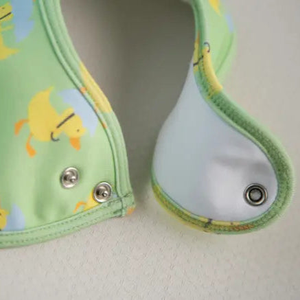 Green baby bib with yellow duck characters on a light  background